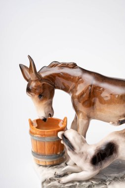 figurine of a donkey that drinks water and next to it a dog teases a donkey