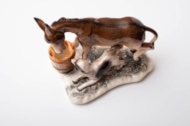 figurine of a donkey that drinks water and next to it a dog teases a donkey