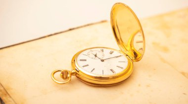 Eski, açık bir kitaptaki klasik bir altın cep saati..