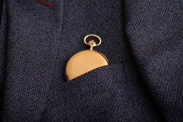 Golden pocket watch on the background of a man's suit. Retro style and vintage fashion.