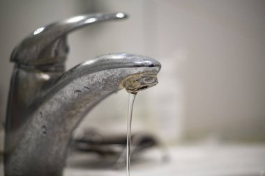 Banyo musluğu eski, kirli, plaka ve pas içinde, kirli su konsepti.