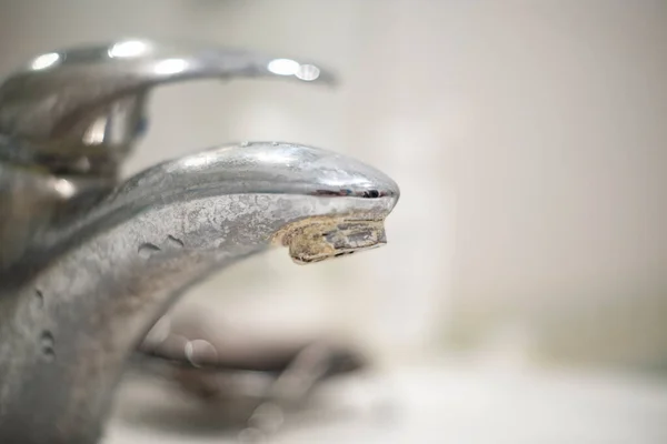 Banyo musluğu eski, kirli, plaka ve pas içinde, kirli su konsepti.