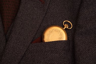 Golden pocket watch on the background of a man's suit.Retro style and vintage fashion.