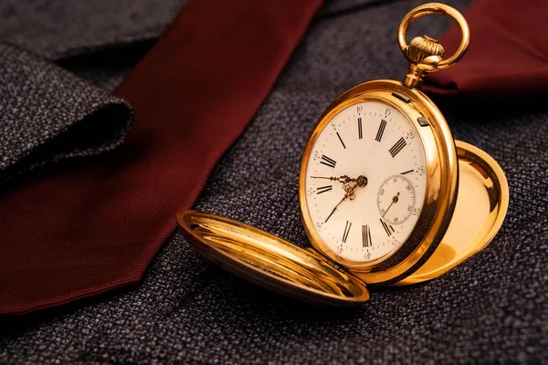 Golden pocket watch on the background of a man\'s suit.Retro style and vintage fashion.