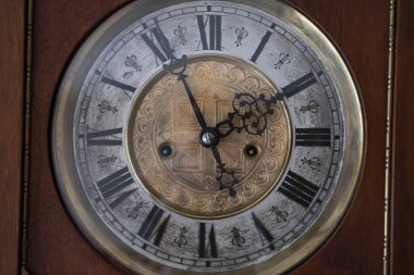 Old wooden clock with a pendulum hanging on the wall