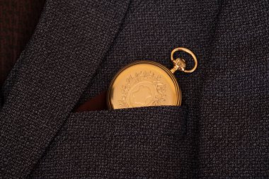 Golden pocket watch on the background of a man's suit.Retro style and vintage fashion.