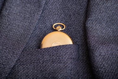 Golden pocket watch on the background of a man's suit.Retro style and vintage fashion.