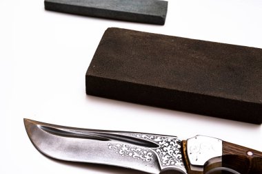 Bıçak keskinleştirme, izole edilmiş beyaz arka planda bıçak aşındırıcı taşla. Bıçak keskinleştirme ustası konsepti.