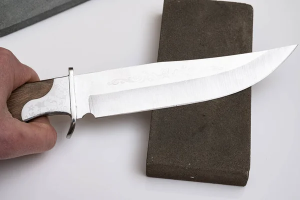 knife sharpening, knife on isolated white background with abrasive stone. the concept of the work of a knife sharpening master