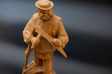 Siyah arka planda el yapımı ahşap bir heykel. Büyükbaba samanlıkta tırpanla geziyor.