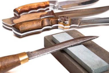 Bıçak keskinleştirme, izole edilmiş beyaz arka planda bıçak aşındırıcı taşla. Bıçak keskinleştirme ustası konsepti.