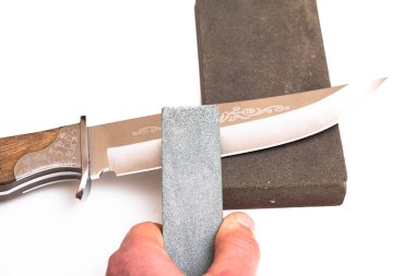 Bıçak keskinleştirme, izole edilmiş beyaz arka planda bıçak aşındırıcı taşla. Bıçak keskinleştirme ustası konsepti.