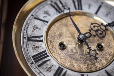 Old wooden clock with a pendulum hanging on the wall