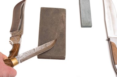 Bıçak keskinleştirme, izole edilmiş beyaz arka planda bıçak aşındırıcı taşla. Bıçak keskinleştirme ustası konsepti.