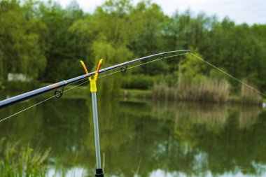 Balıkçı sandalyesi ve olta şafak vakti gölün üzerinde arka planda. Balık tutma konsepti. Güzel gün doğumu - sabah manzarası. Siste oltası olan bir balıkçının mekanı.