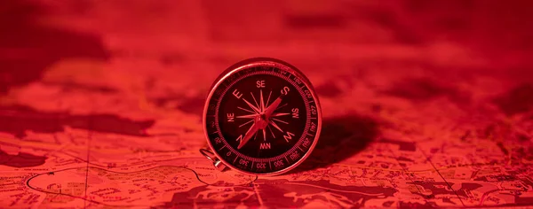 compass on the background of the map in the red light of danger. travel concept. route planning. find your direction in life