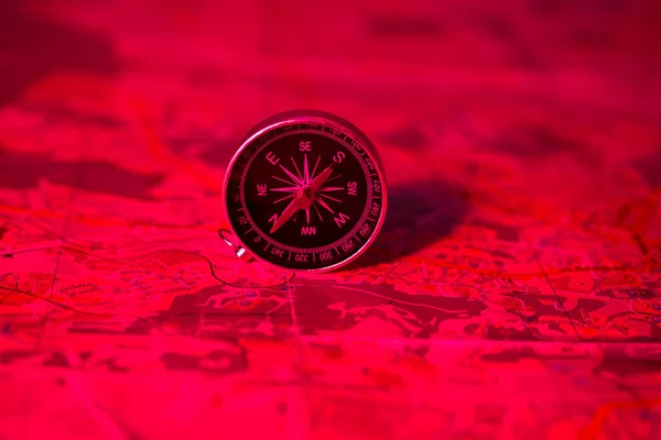 compass on the background of the map in the red light of danger. travel concept. route planning. find your direction in life