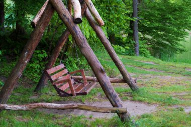 Parkta dinlenmek için tahta salıncak. Kamp yapmak. Parkta salıncakta sallanmak. Turistler için ormanda kütüklerle sallan..