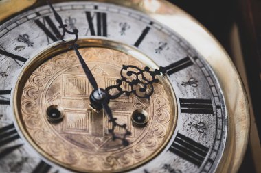 Old wooden clock with a pendulum hanging on the wall