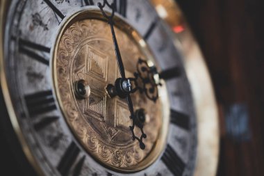 Old wooden clock with a pendulum hanging on the wall