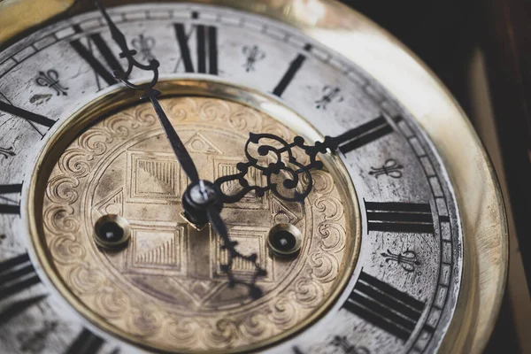Old wooden clock with a pendulum hanging on the wall