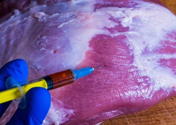 stock image Injection from a syringe into raw meat on a dark background.Conceptual illustration of hormones and antibiotics in food production.