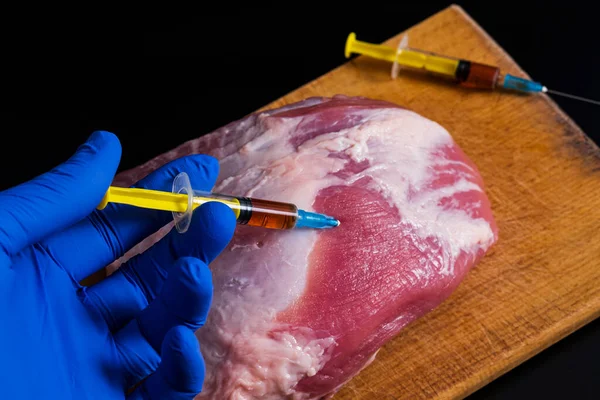 Siyah arka planda çiğ ete bir şırıngadan enjekte edildi. Gıda üretiminde hormonların kavramsal çizimi ve antibiyotikler.