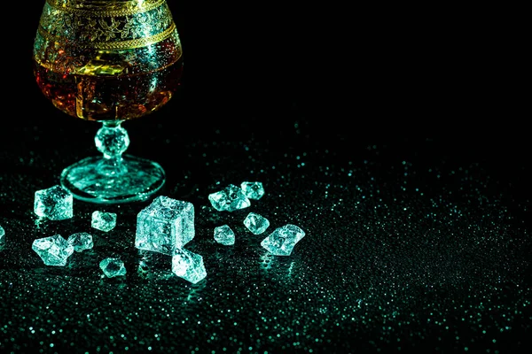 stock image Glass with cognac and ice on a dark background. the concept of alcoholism and drinking