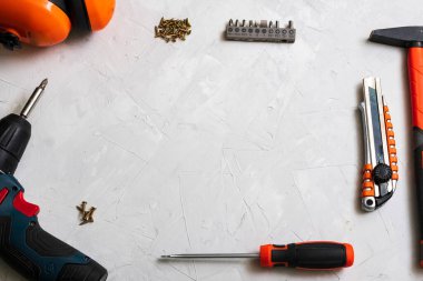Çalışma araçları, çekiç, tornavida, pense, elektrikli matkap, mezura, beyaz arka planda vidalar üst görünüm.