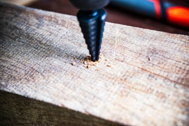 Ahşap arka planda basamaklı koni matkabı.