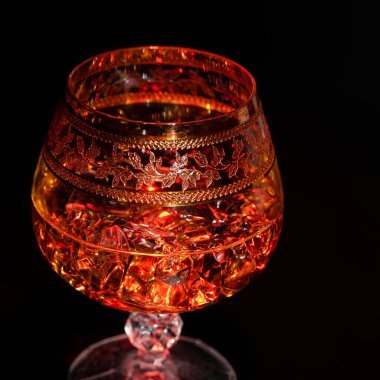 Koyu arkaplanda konyak ve buzlu bir bardak. Alkolizm ve içki kavramı