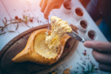 Şef aşçı ya da garson peyniri çatal ve bıçakla karıştırır.