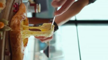 Şef aşçı ya da garson peyniri çatal ve bıçakla karıştırır.