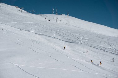 Alp karlı tepelerde kayak yapan kayakçılar ve snowboardcular