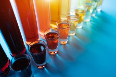 various colorful alcoholic drinks with shooters and transparent bottles