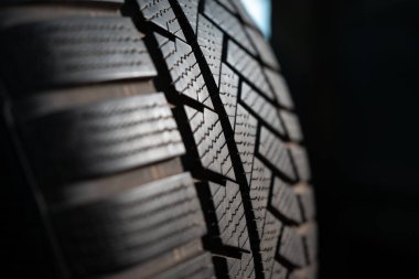 closeup of modern rubber tyre for automobile wheel at auto store, tread pattern, replacement tire service concept