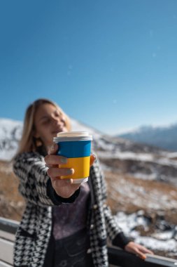 blonde woman drinking hot tea in mountains
