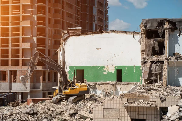 bulldozer ruins house near construction of new brick tower building