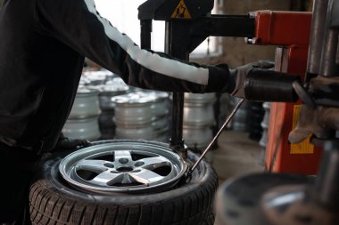 Otomatik tamir servisindeki alet ve makine teçhizatıyla lastiği jantından çıkaran mekaniker görüntüsü.