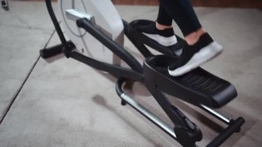 Spor kulübündeki eliptik yörünge makinesi üzerinde egzersiz yapan yakın plan kadın ayakları