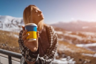 blonde woman drinking hot tea in mountains