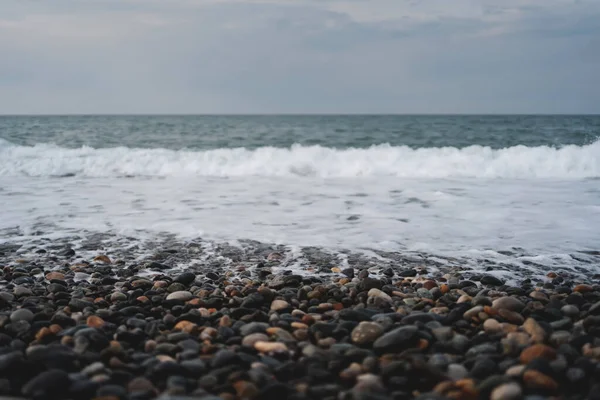 stock image sea or oceanic beach with black, brown and grey pebbles, background wallpaper