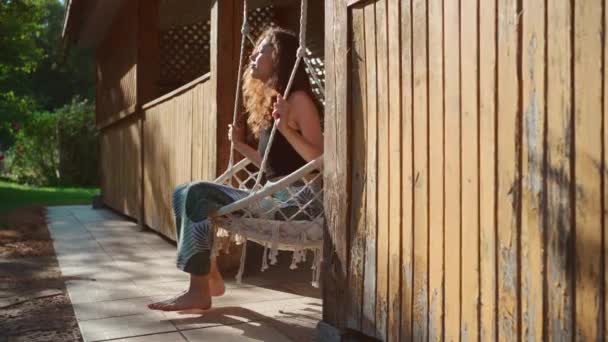 夏天的时候 赤脚姑娘坐在挂着的针织吊床上 在花园里荡秋千 在大自然中休息 — 图库视频影像