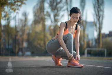 Güzel kıvırcık kadın gün batımında açık hava antrenmanından önce ısınıyor.
