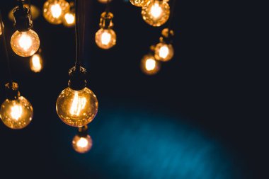 Karanlık odada tavana asılmış eski el işi ampuller.