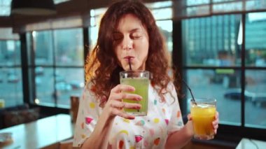 Kıvırcık saçlı güzel bir kız elinde kokteyller ya da farklı limonata tadı olan bir kız.