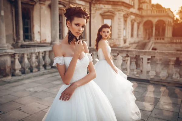 2人のスタイリッシュな花嫁ファッションモデルの女の子のカップルは古代の城でポーズ 結婚式の写真セッション — ストック写真