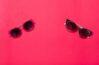 Kırmızı ya da pembe arka planda uzanan lüks ve şık güneş gözlükleri düz bir şekilde duruyordu. Yüksek kalite fotoğraf