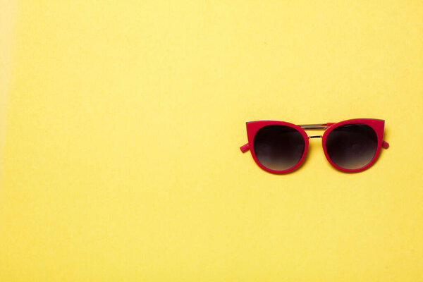 luxury and stylish fashionable sun glasses lying on yellow background, flat lay top view. High quality photo