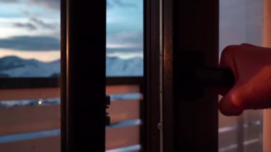 Perde ve pencere açık ve dağ evinde gün batımına ya da güneşin doğuşuna bakan kişi. Yüksek kaliteli FullHD görüntüler